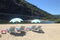 Flower Camping Le Riviera - Sandstrand vom Campingplatz am Fluss mit Liegestühlen, Sonnenschirmen und Blick auf Berge