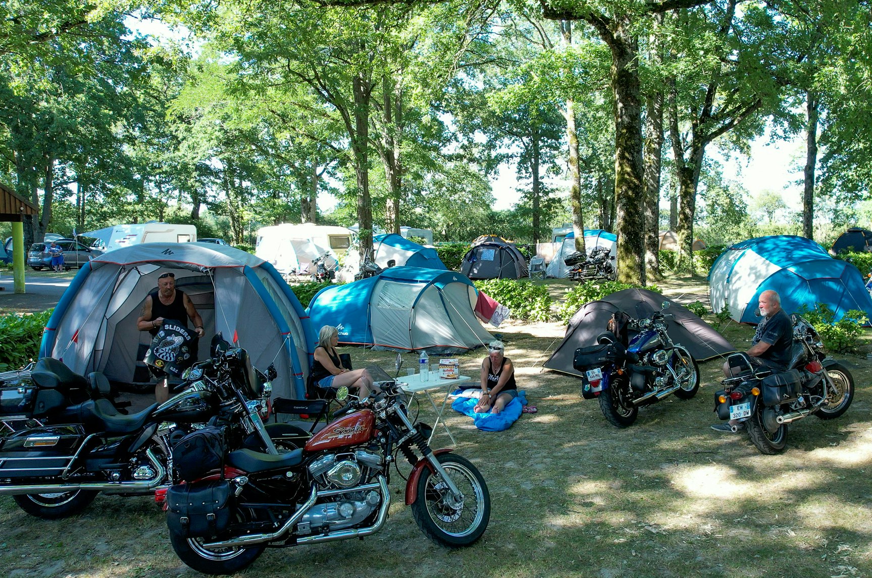 Camping des Étangs  Flower Camping Les Étangs - Camper mit Motorrädern auf der Zeltwiese