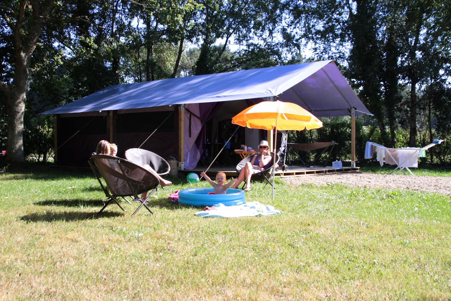Flower Domaine de Mesqueau - Glamping Zelt mit davor sitzender Familie auf dem Campingplatz