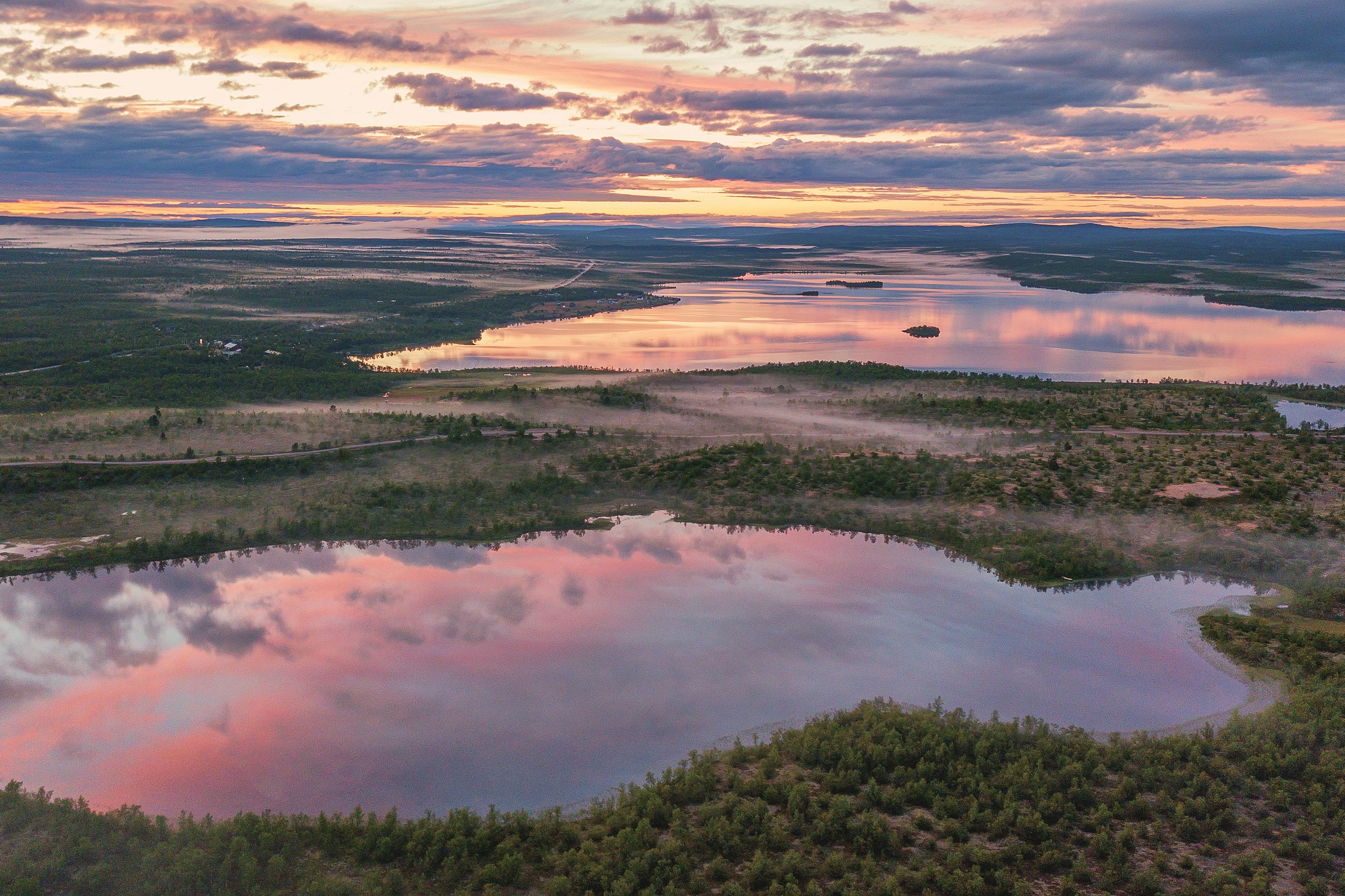 Fluss und See in einer weiten Landschaft, Blick von oben bei Sonnenuntergang mit Wolken und Ufervegetation.