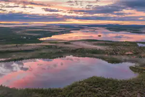 Fluss und See in einer weiten Landschaft, Blick von oben bei Sonnenuntergang mit Wolken und Ufervegetation.