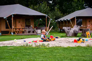 Glamping de Bosweide - Kinder spielen im Sandkasten vor den Glamping-Unterkünften