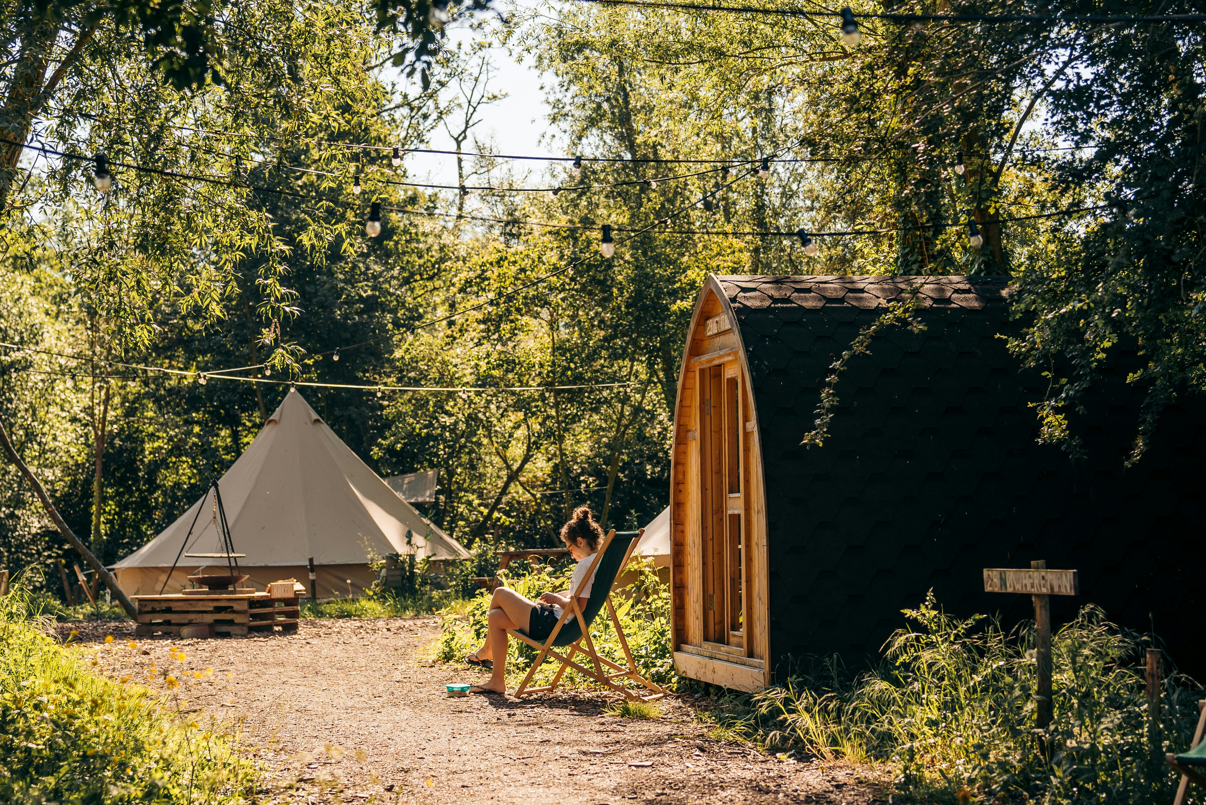 Glamping Oord RØSTIG - Camperin entspannt in einem Stuhl vor einer Mietunterkunft