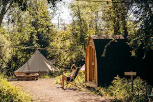 Glamping Oord RØSTIG - Camperin entspannt in einem Stuhl vor einer Mietunterkunft