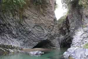Eine Felsenschlucht mit türkisfarbenem Wasser, umgeben von steilen Felswänden und Bäumen am Ufer.