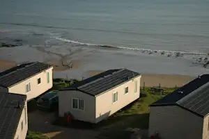 Mobile Homes mit Solardächern am Campingplatz, Blick auf den Strand und das Meer.