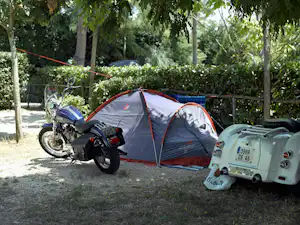 Campingzelt mit orangefarbenem Rand, davor Motorrad und Oldtimer im Grünen zwischen Bäumen und Hecken.