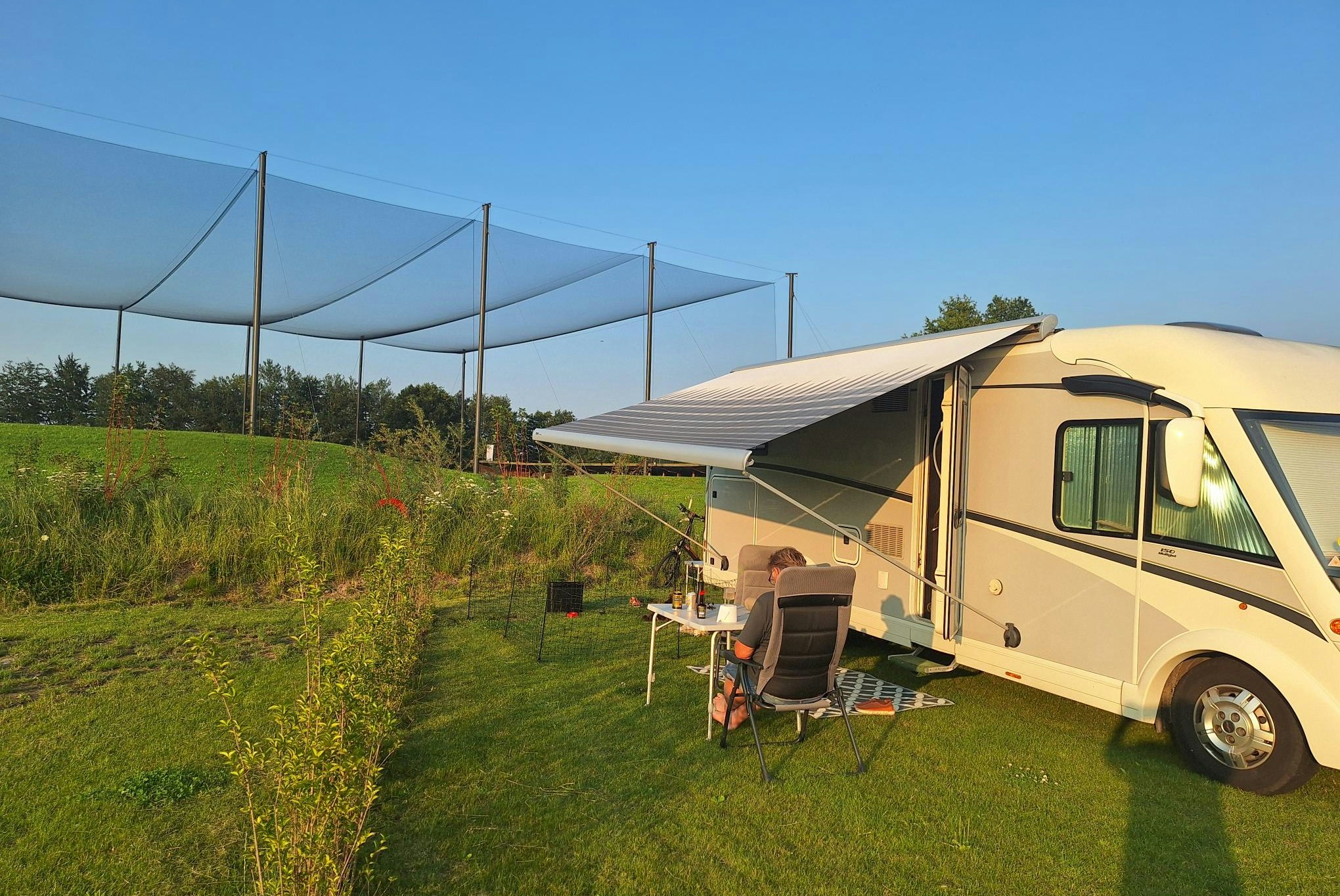 Harderwold Villa Resort - Camper sitzt vor seinem Wohnmobil auf seinem Standplatz