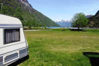 Hellesylt Camping  -  Wohnwagen auf dem Stellplatz vom Campingplatz mit Blick auf den Fjord und schneebedeckte Berge