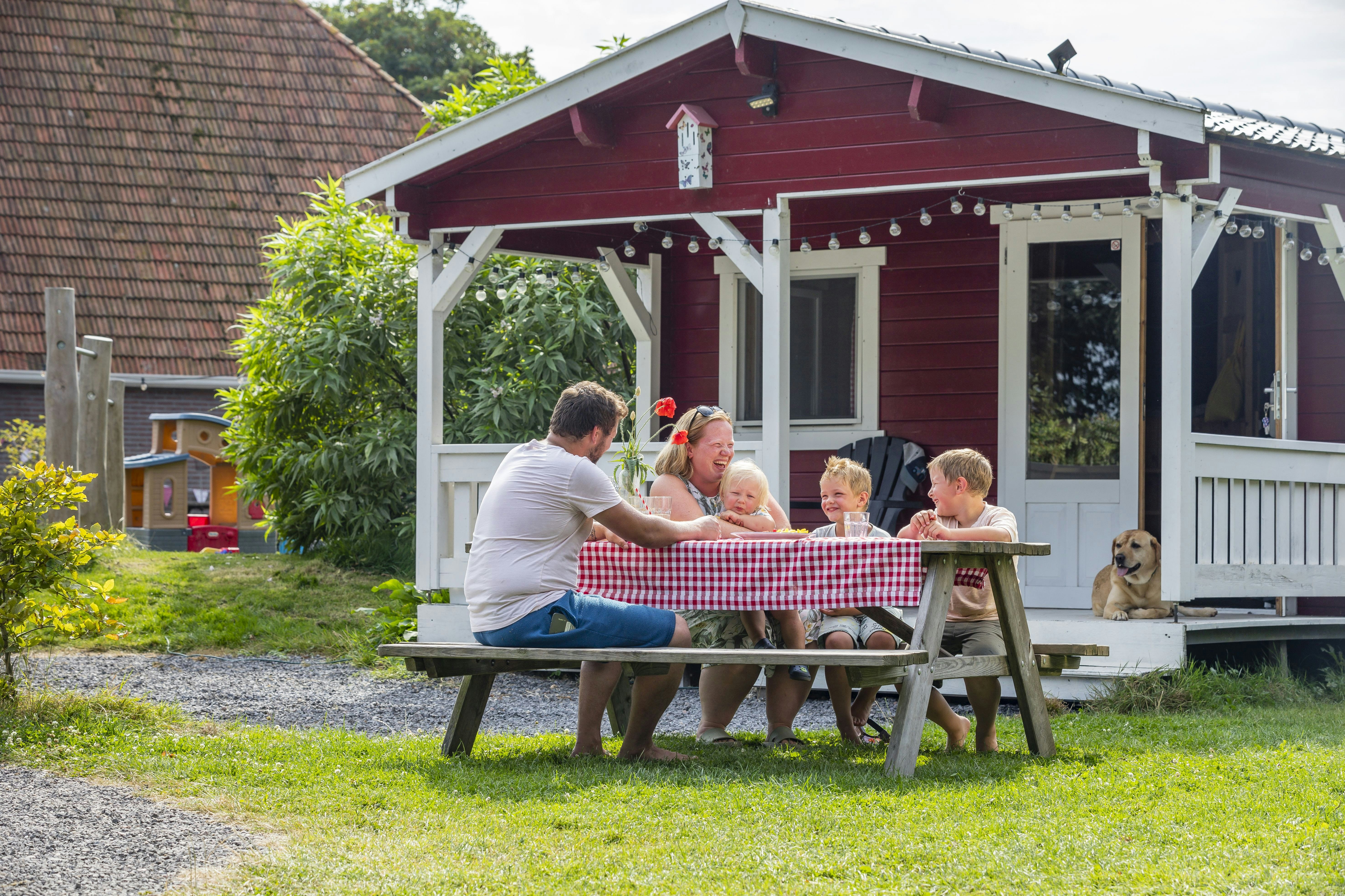 Camping De Bolderik  Het Zwerversnest - Familie sitzt an einem Picknicktisch auf dem Campingplatz