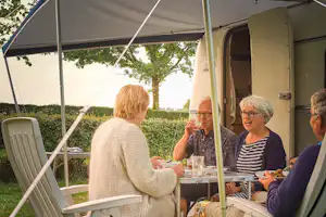 Hoeve de Gastmolen - Camper sitzen vor dem Wohnmobil im Schatten der Markise