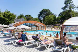 Schwimmbecken auf dem Campingplatz mit Holzbogen, Sonnenschirmen und Liegestühlen, Kinder planschen im Wasser.