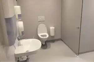 Camping-Badezimmer mit Waschbecken, Toilette, Spendern und Wandarmaturen in heller, moderner Ausstattung.