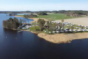 Campingplatz am Flussufer mit vielen Stellplätzen und Wohnwagen, Blick von oben auf das Wasser und die Uferbäume.