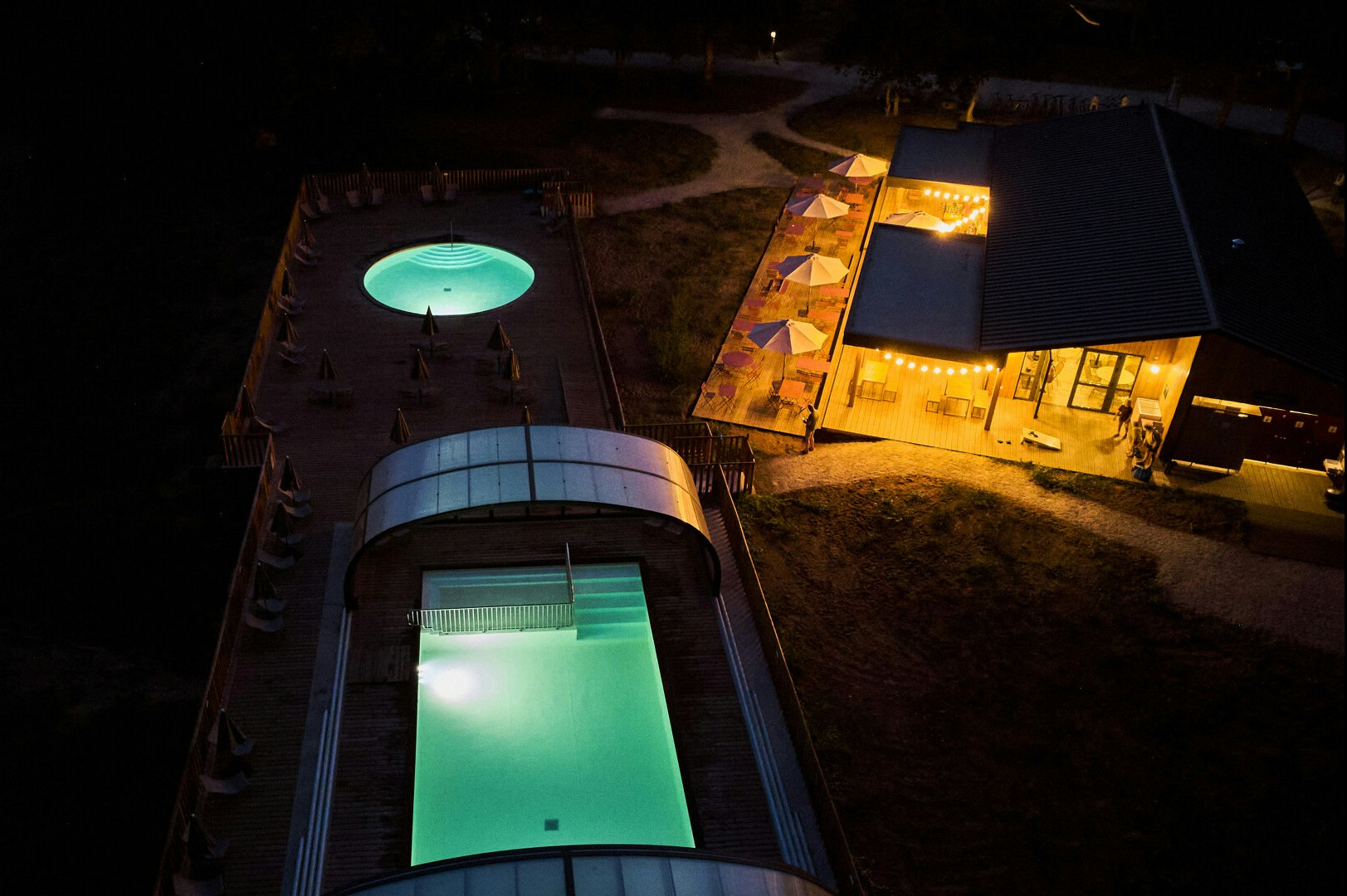 Huttopia Caminos de Galicia - Luftaufnahme des Pools bei Nacht