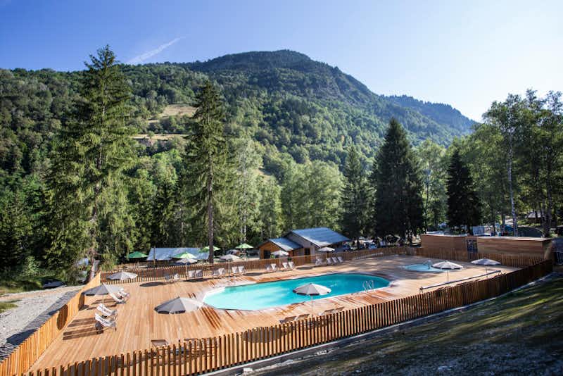 Huttopia Camping Bozel en Vanoise - Poolbereich mit Liegestühlen und Sonnenschirmen mit Blick auf die Berge 