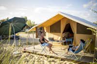Huttopia Camping Côte Sauvage - Camperpaar vor ihrem Glampingzelt  in der Sonne