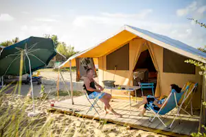 Huttopia Camping Côte Sauvage - Camperpaar vor ihrem Glampingzelt in der Sonne