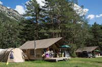 Huttopia Camping La Clarée - Glamping Zelt zwischen Bäumen mit Blick auf Berge auf dem Campingplatz