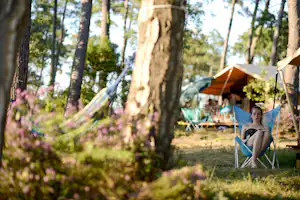 Huttopia Landes Sud - Gaste lese im Schatten der Bäume.