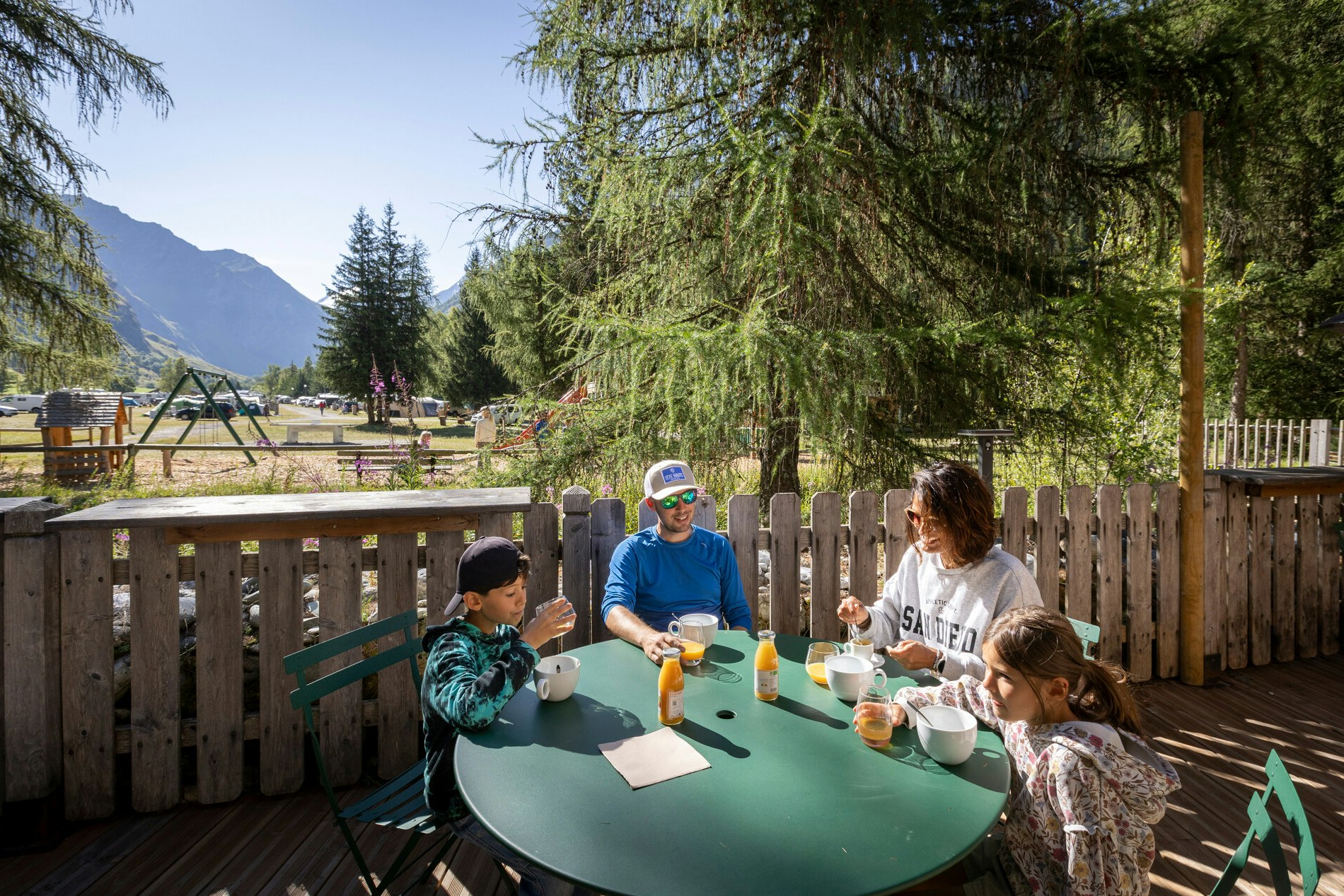 Huttopia Vanoise - Champagny  Huttopia Vanoise – Champagny - Familie frühstückt gemeinsam auf der Terrasse des Campingplatzes