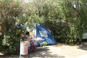 Hydra's Wave Camping - Zelt mit davor sitzenden Campern zwischen Bäumen