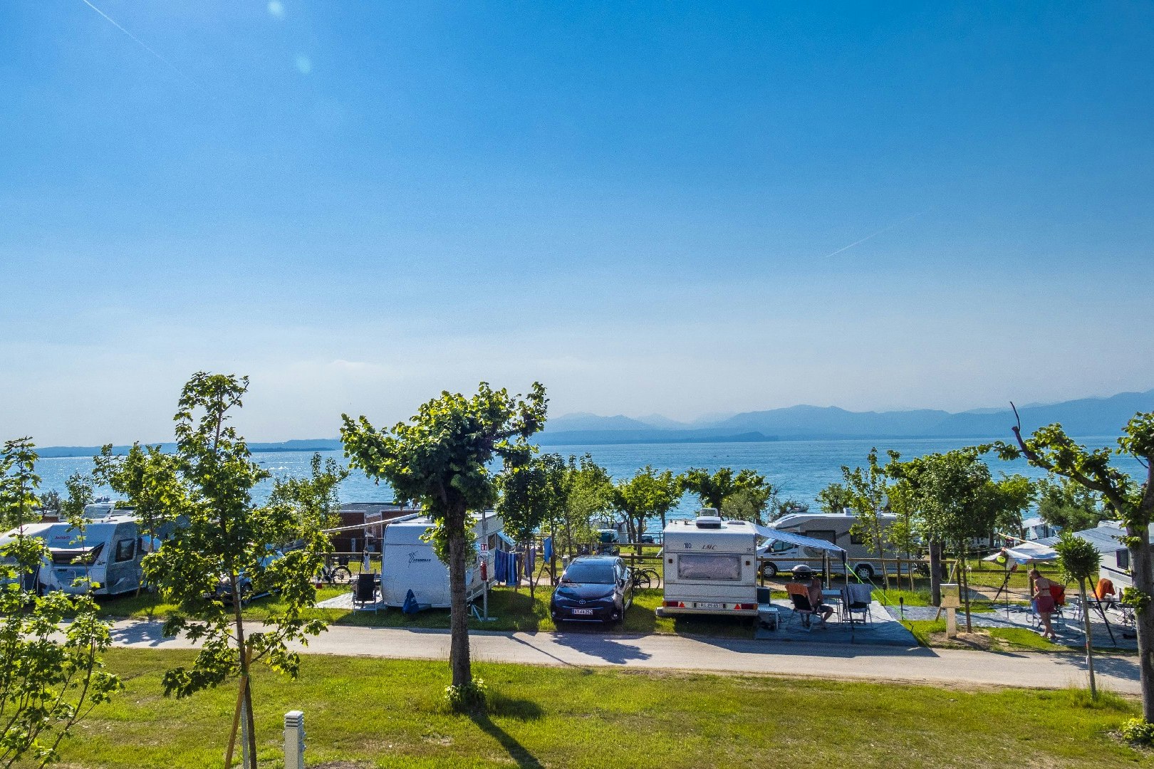 Idea Lazise Camping & Village - Gäste vor ihrem Wohnmobil mit Blick aufs Wasser