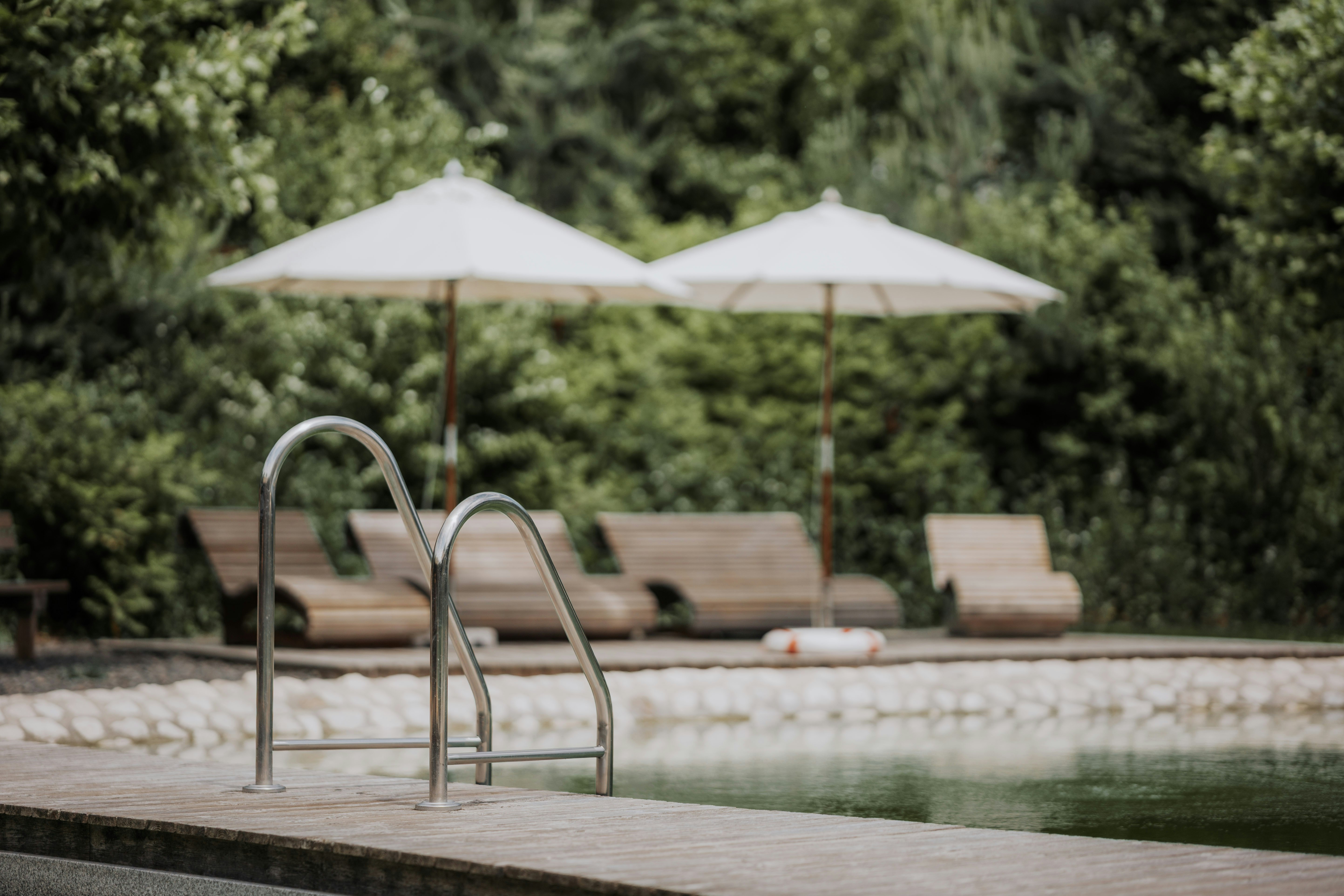 IKUNA Camping Resort - Naturschwimmteich und Liegestühle mit Sonnenschirmen