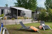 Camping Les Iles  -  Mobilheim vom Campingplatz mit Veranda, Liegestühlen und Fahrrad auf grüner Wiese