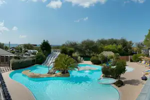 Camping Les Iles - Pool vom Campingplatz mit Wasserrutsche, Sonnenschirmen und Liegestühlen