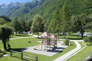 Kamp Soča - Blick über den Campingplatz mit Spielplatz im Vordergrund, Zeltwiese und Wohnwagenstellplatz, im Hintergrund die Alpen