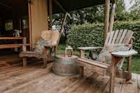 Kampari Safarizelt-Mietunterkunft mit teilweise überdachter Veranda und rustikalen Sitzmöglichkeiten