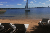Kempingas Slėnyje - Segelboot im See und Liegestühle am Strand des Sees vor dem Campingplatz