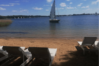 Kempingas Slėnyje - Segelboot im See und Liegestühle am Strand des Sees vor dem Campingplatz