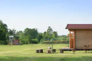 Camping Paberzi - Holzbungalow mit großer Rasenfläche und Volleyballnetz