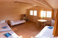 Camping Paberzi - Innenansicht des Mobilheims mit vier Betten und einem Tisch 