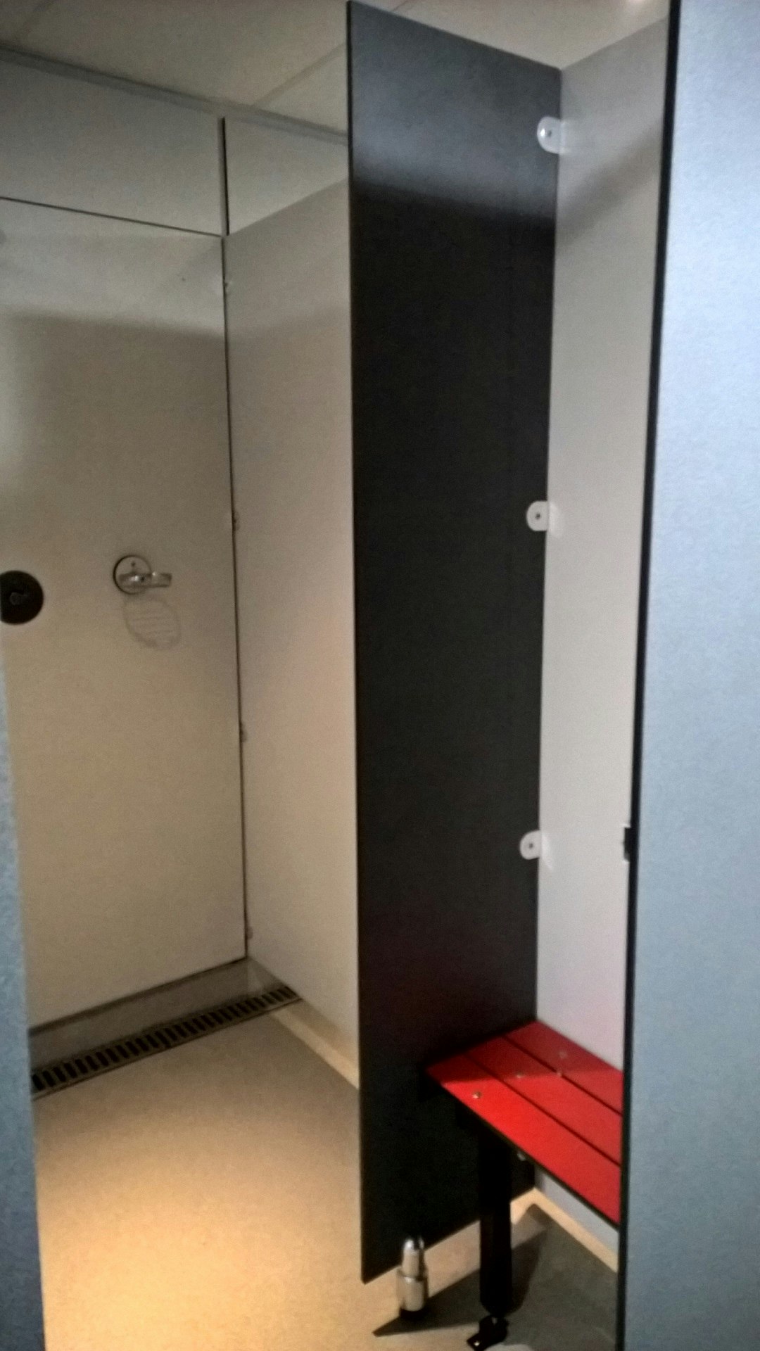Innenraum mit Schranktür und Bank mit roter Sitzfläche, daneben kleine Ablage und Wandpaneele.