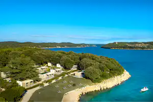 Campinganlage an einer Bucht mit Küste, weißen Gebäuden, Stellplätzen und Blick aufs Meer und die Inseln.