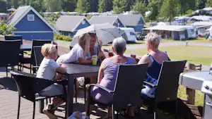 Krakær Camping - Camper sitzen im Restaurant Terrasse mit Blick auf die Wohnwagenstellplätze