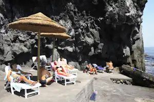 La Timpa International Camping - Camper auf den Liegestühlen unter Sonnenschirmen am Meer auf dem Campingplatz