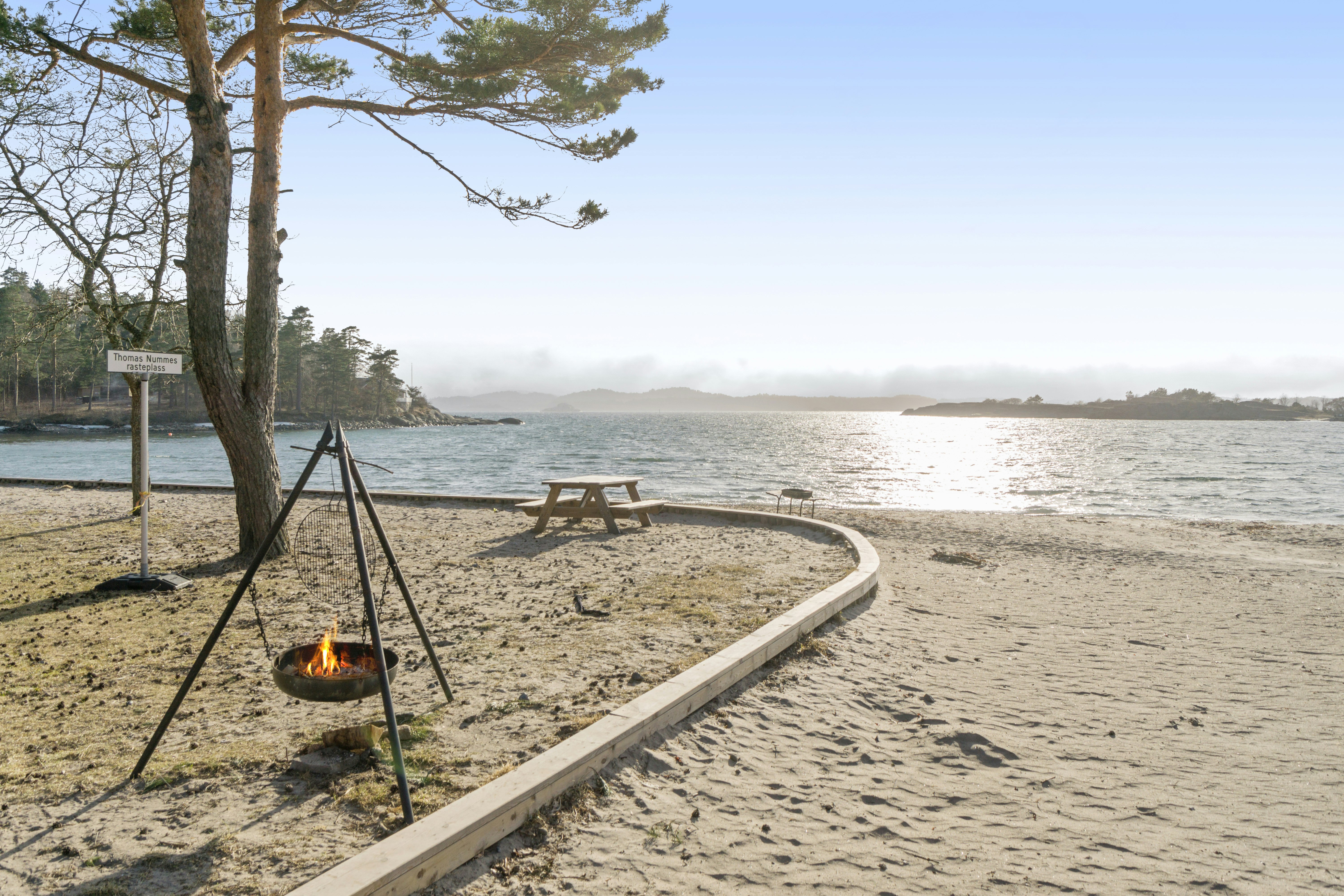 Langeby Camping - Blick auf den Strand mit Feuerschale und Picknickbank