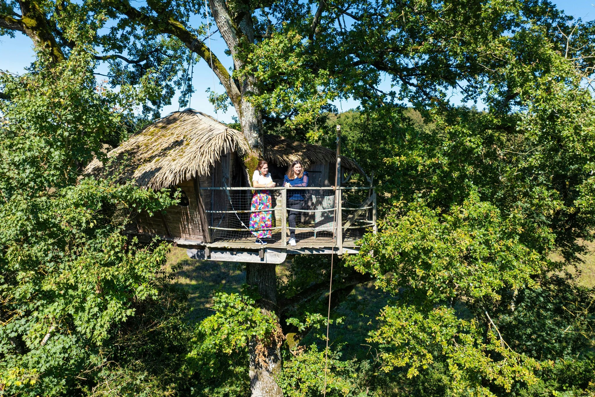 Le Parc de la Belle - Camperinnen genießen die Aussicht von der Terrasse eines Baumhauses