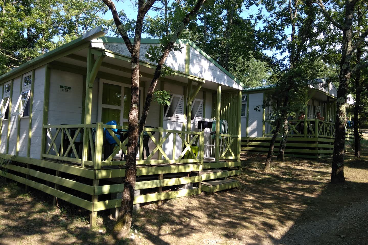 Camping Le Roc del Rey  - Mobilheim mit Veranda und Esstisch im Schatten der Bäume