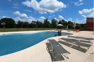 Le Village de Cottages - Freibad mit Liegestühlen auf dem Campingplatz