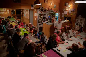 Eine Gruppe sitzt an Tischen in einer Holzlounge und spielt gemeinsam ein Brettspiel.
