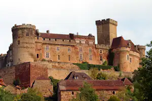 Alte Burganlage mit mehreren Türmen und Zinnen, umgeben von historischen Häusern im Stadtbild.