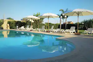 Lilybeo Village - Schwimmbad mit Liegestühlen umgeben von Bäumen
