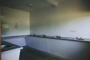 Küchenzeile mit mehreren Spülbecken und Armaturen in einem hellen Sanitärraum am Campingplatz.
