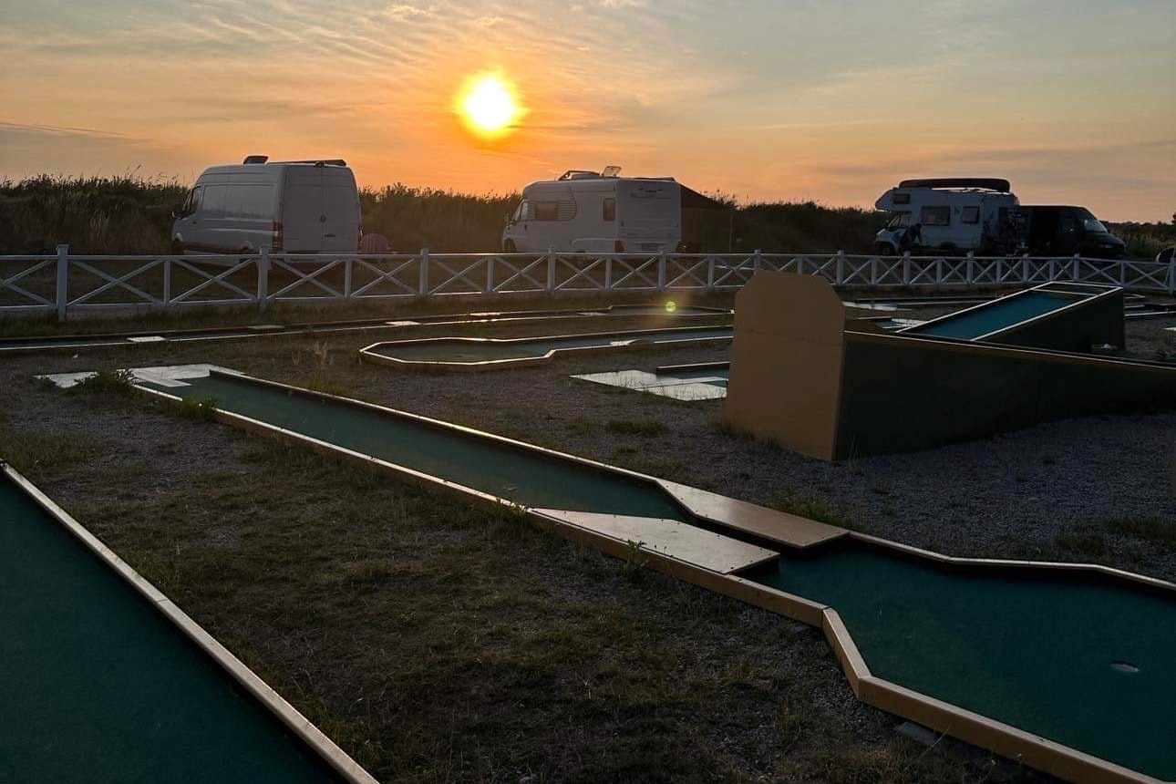 Lomma Camping & Resort - Minigolfanlage mit Blick auf die Standplätze bei Sonnenuntergag
