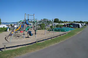 Lærkelunden Camping - Spielplatz vom Campingplatz mit Rutsche und Trampolin mit Blick auf das Meer